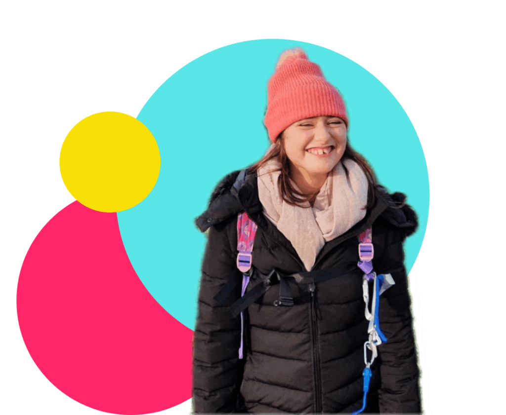 Girl with backpack and pink beanie smiling.